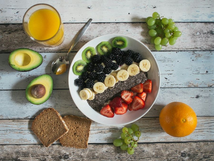 Bol de fruits et graines de chia, pain complet et jus d’orange